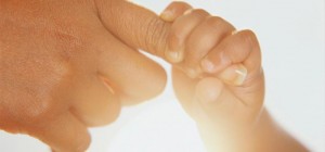 a babys hand grasps the mothers index finger