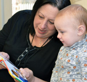 toddler enjoying a book with a teacher