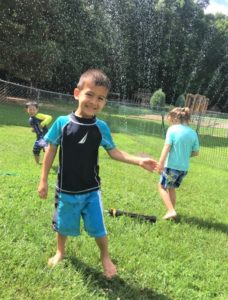 child playing in sprinklers