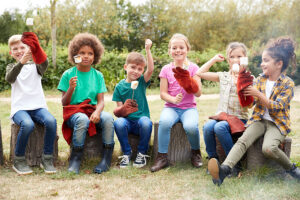 Children sitting on a log camping trip