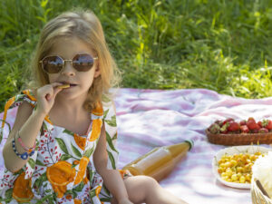 a girl sitting on a blanket outside having a picnic