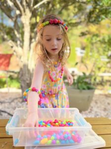 girl outside making bead jewellery