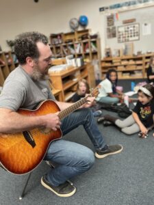 Teacher playing guitar to students