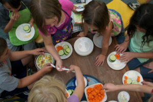 children around a table with vegetables making a meal